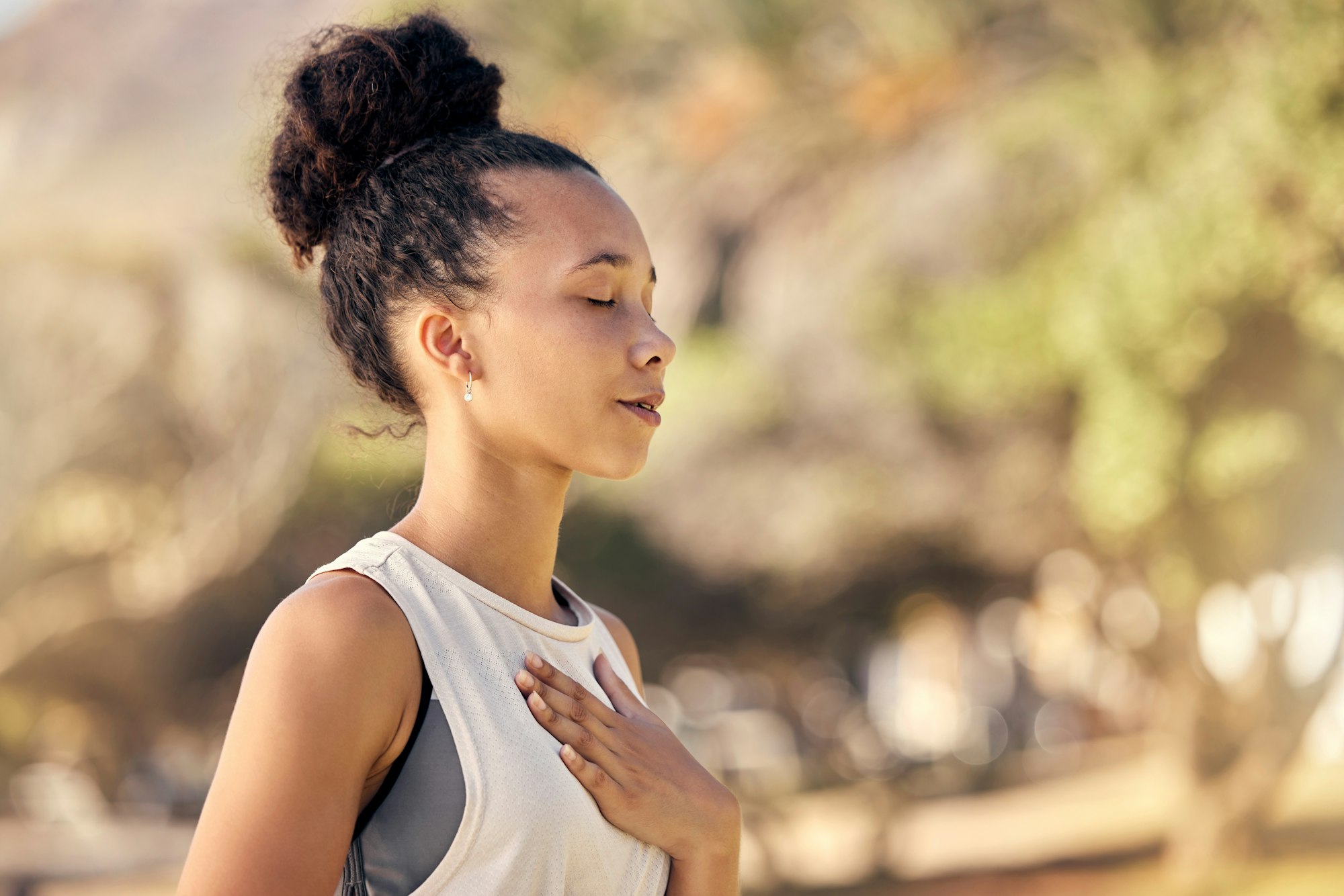 Black woman, breath and hand on chest, for meditation and wellness being peaceful to relax. Bokeh,