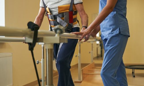 Stroke patient walks between parallel bars at rehabilitation room